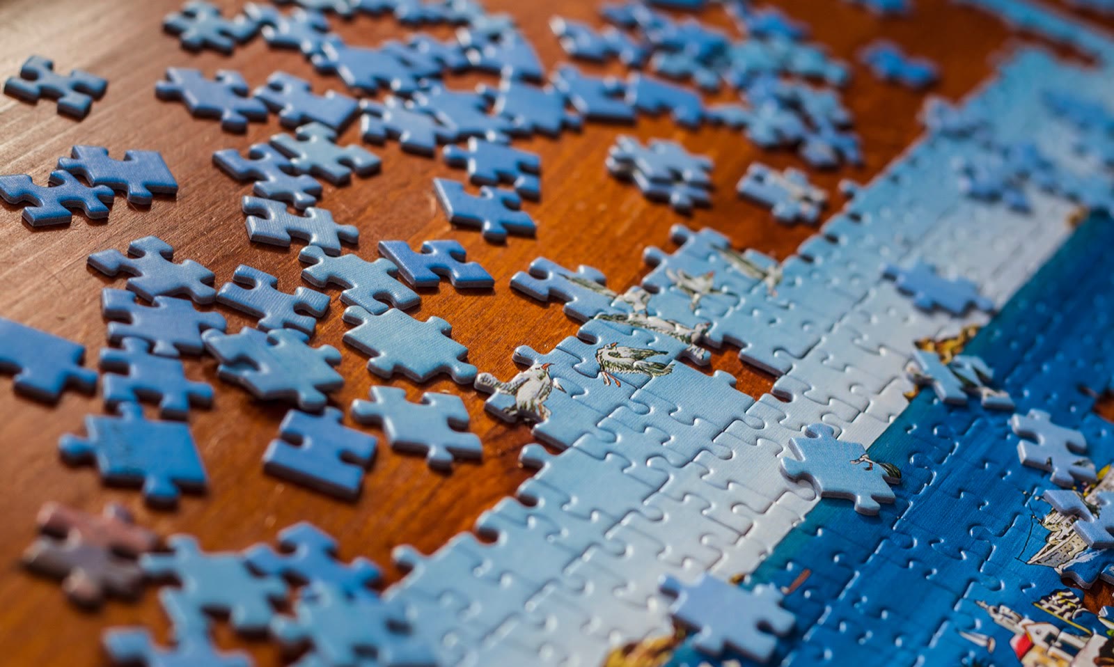 A jigsaw puzzle mid-assembly: loose blue pieces scattered around a partially completed edge